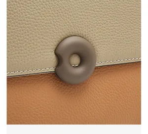 Detailed view of women leather handbag featuring contrast color texture and round clasp.