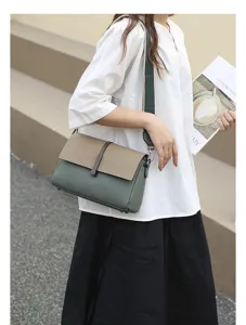 Detail shot of stylish color-block leather crossbody bag with wide strap and chic design.