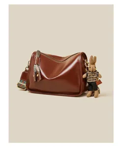 Brown vintage leather crossbody bag with ethnic strap and cute rabbit pendant detail view.