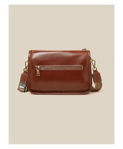 Detailed view of brown leather crossbody bag back zipper pocket and ethnic strap hardware.