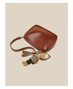 Retro brown shoulder bag detail featuring a cute rabbit doll pendant and stylish scarf accessory.