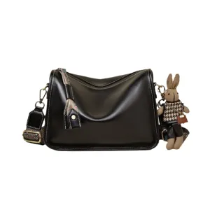 Elegant black leather bucket bag for women, retro crossbody bag with rabbit doll charm.