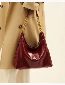 Burgundy patent leather shoulder hobo bag detail, featuring elegant gold chain strap design.
