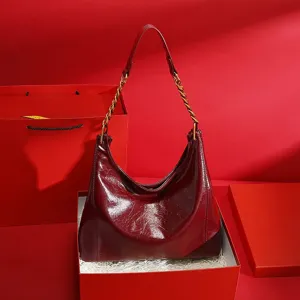Red patent leather shoulder bag detail with metallic chain strap and gift box setup.