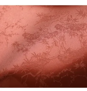 Close-up detail of red satin fabric with traditional pine tree jacquard pattern and texture.