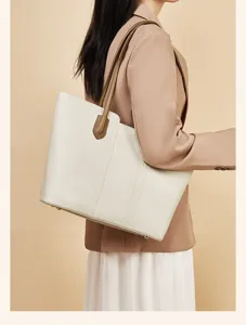 Detailaufnahme einer stilvollen weißen Tote-Tasche mit braunen Ledergriffen und klarem Design.