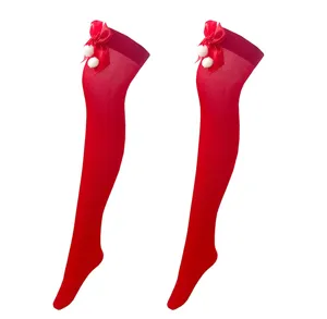 Detailansicht roter Weihnachtsstrümpfe über dem Knie mit Schleife und kleinen Bommeln.