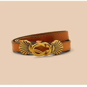 Gedetailleerd overzicht van een dunne lederen riem met vintage messing gesp voor jurken.