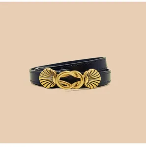 Gedetailleerd uitzicht op de donkerblauwe smalle lederen riem met elegante gouden schelp gesp.
