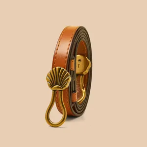 Elegante bruine lederen smalle damesriem voorzien van een stijlvolle gouden schelp gesp.