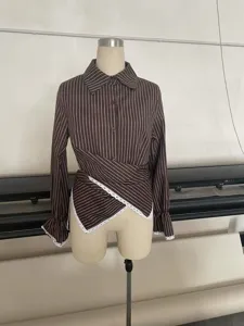 Detailed view of women's striped long-sleeve shirt featuring a stylish cross-waist and lace hem.