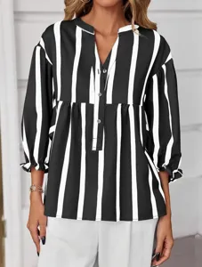 Detail view of the black and white vertical striped blouse with chic puff sleeves and V-neck.