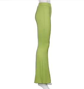Side detail view of solid green high-waisted micro flare trousers with black side piping.
