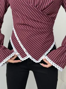 Detail view of women's maroon striped wrap long sleeve blouse with delicate white lace trim.