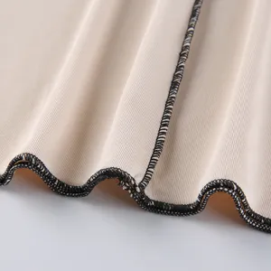Close-up detail shot of ribbed knit fabric, highlighting delicate lettuce edge hem and texture.