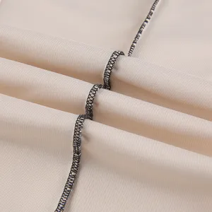 Detailed close-up of women's casual pants fabric featuring neat black contrast stitching.