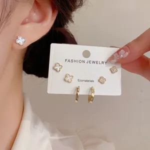 Detailed view of the exquisite clover stud and hoop earring set, worn on ear and hand.