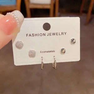 Detailed shot of minimalist square cubic zirconia stud earrings and small hoop set.