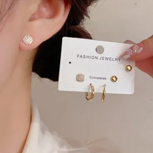 Close-up detail of exquisite zirconia square stud earrings and delicate hoop set worn on ear.