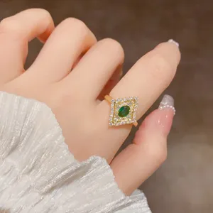 Primo piano dettagliato di anello dorato vintage con pietra verde e zirconi lucenti.
