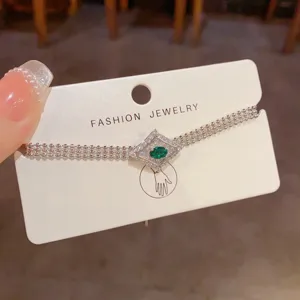 Elegante bracciale in argento multistrato con brillante pietra centrale verde in un chic design a rombo.