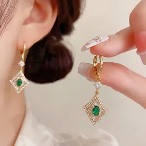 Primo piano dettagliato di orecchini a cerchio rombo con diamante verde