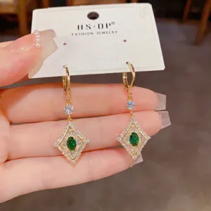 Primo piano dettagliato di eleganti e luminosi orecchini pendenti con pietra verde.