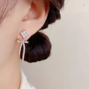 Nahaufnahme Produktdetail der glitzernden Zirkon Schleifen OHRRINGE elegant am Ohr getragen.