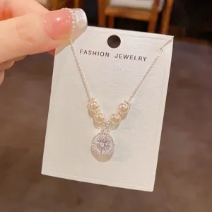 Primo piano del ciondolo collana stella zircone perla argento su carta espositiva, elegante.