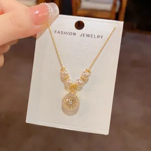 Collana con ciondolo a stella placcato in oro con perle su carta espositiva, gioiello.