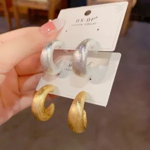 Nahaufnahme von französischen Retro-Metall-C-Ohrringen mit feiner Struktur in Gold und Silber.