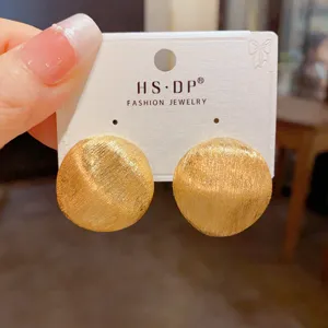 Nahaufnahme der goldenen strukturierten runden Ohrringe, präsentiert auf einer weissen Karte.