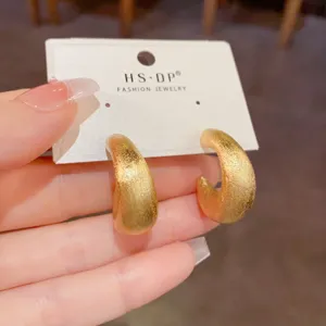 Nahaufnahme von strukturierten goldenen Creolen auf Präsentationskarte, elegantes Design.