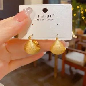 Nahaufnahme goldener gebürsteter Halbreif-Ohrringe auf Karte, elegantes minimalistisches Design.