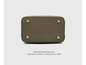 Gros plan sur le fond du sac en cuir de vachette avec pieds en métal, détail élégant et durable.