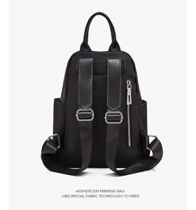 Detailed view of the black nylon backpack showing sturdy leather straps and metal hardware.