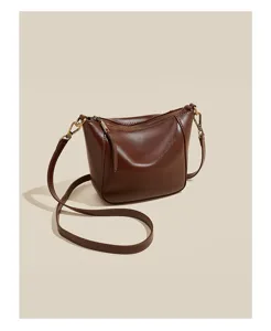 Brown leather crossbody bag detail, smooth oil wax texture, premium metal hardware and zipper.