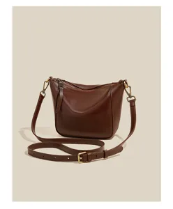 Close-up of brown leather shoulder bag showing fine texture and adjustable strap.