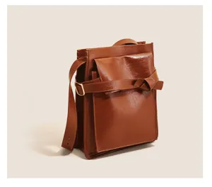Detailed view of brown shoulder bag with knot strap design and metal buckle hardware.