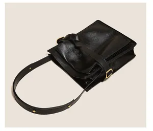 Detailed view of black vintage commute shoulder bag with glossy finish and stylish buckle strap.