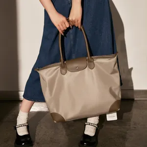 Detail view of the elegant nylon tote handbag featuring brown leather handles and flap.