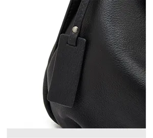Close-up view of premium black genuine leather handbag detailing texture and metal hardware.