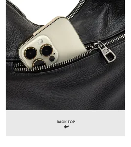 Detailed view of the back zipper pocket on the black leather shoulder bag, holding a phone easily.