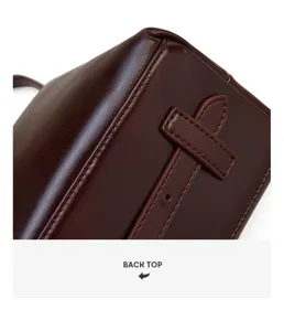 Close-up detail shot of the dark brown leather commuter bag showing back top strap design.