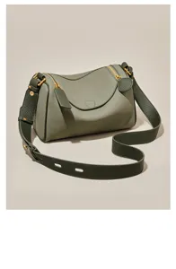 Close-up detail of olive green leather pillow bag showing smooth curved zipper and texture.
