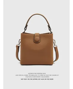Vue détaillée du sac seau en cuir marron, montrant une texture premium, une poignée et une sangle.