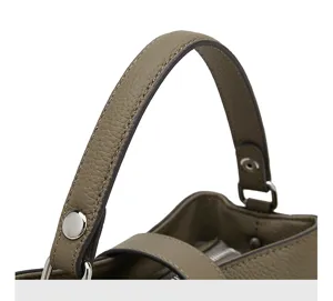 Gros plan sur la poignée du sac-seau en cuir véritable, coutures soignées et bouton-pression.
