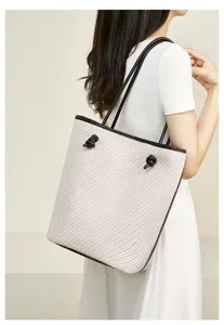 Detail shot of large capacity woven shoulder tote bag featuring black leather straps and chic knots.
