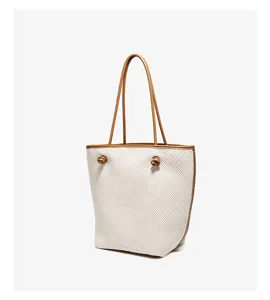 Detailed close-up shot of the woven bucket handbag showcasing brown leather trim and chic knots.
