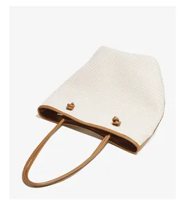 Detailed shot of casual straw woven shoulder bag with brown leather trim and cute knot decor.